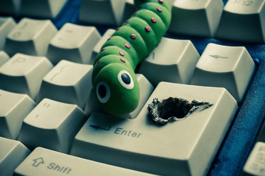 An image of a worm coming out of a hole on a keyword is a representation of a virus living inside of the computer
